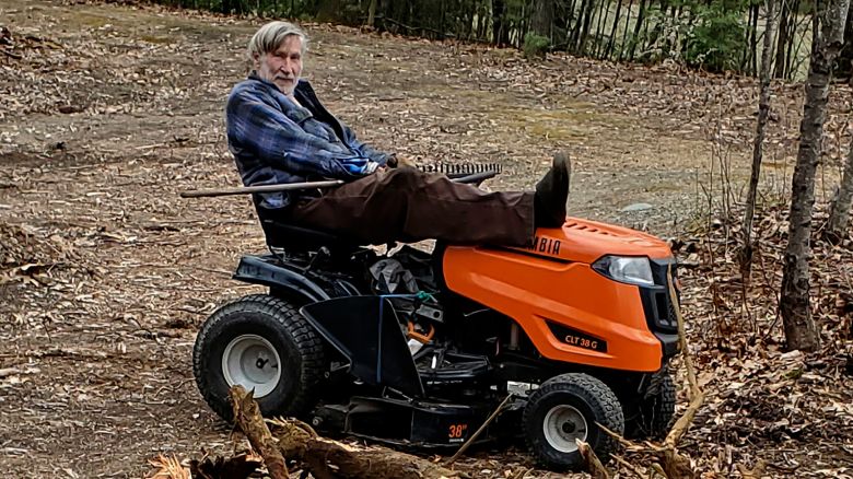 In this photo Geoffrey Holt rests his leg on top of his riding mower in Hinsdale, N.H., on April 4, 2020. Holt left the town of Hinsdale nearly $4 million when he died last June.